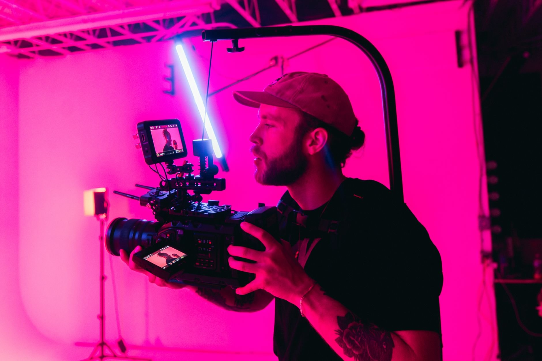 Creator filming video content in a neon-lit studio with professional camera setup